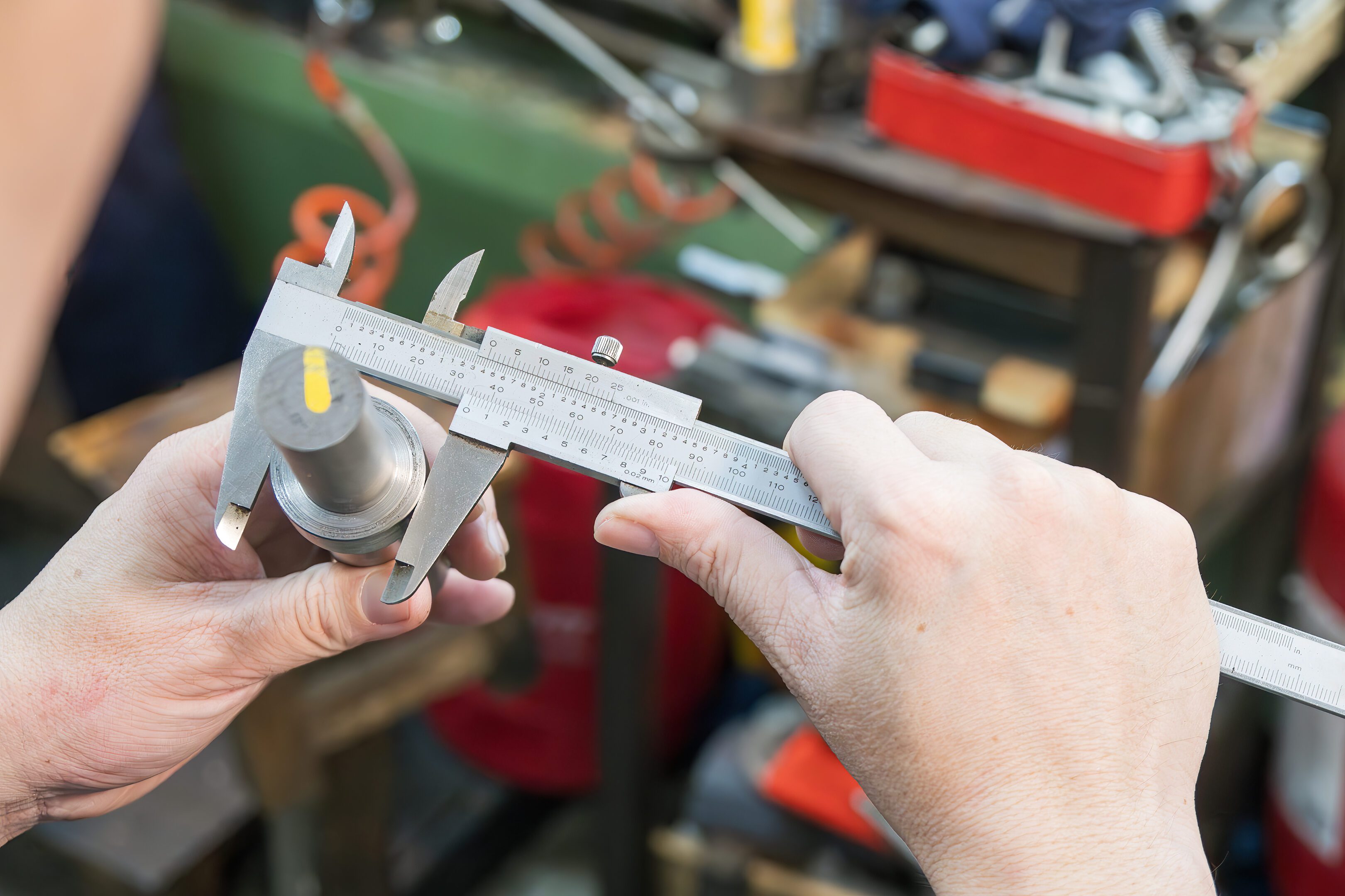 Hands using caliper to measure object.